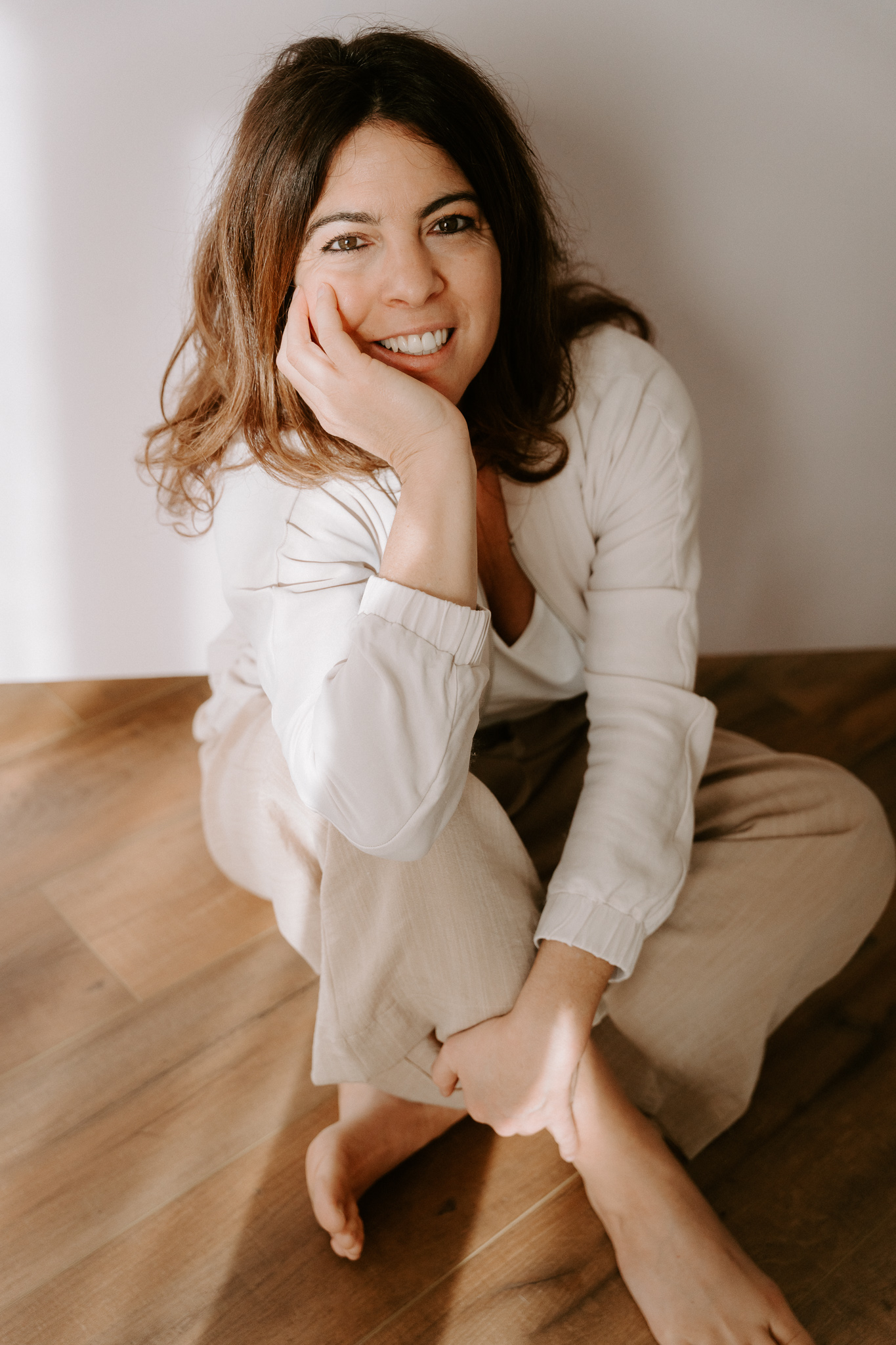 Eine Frau sitzt auf dem Boden und schaut lächelnd an der Kamera vorbei