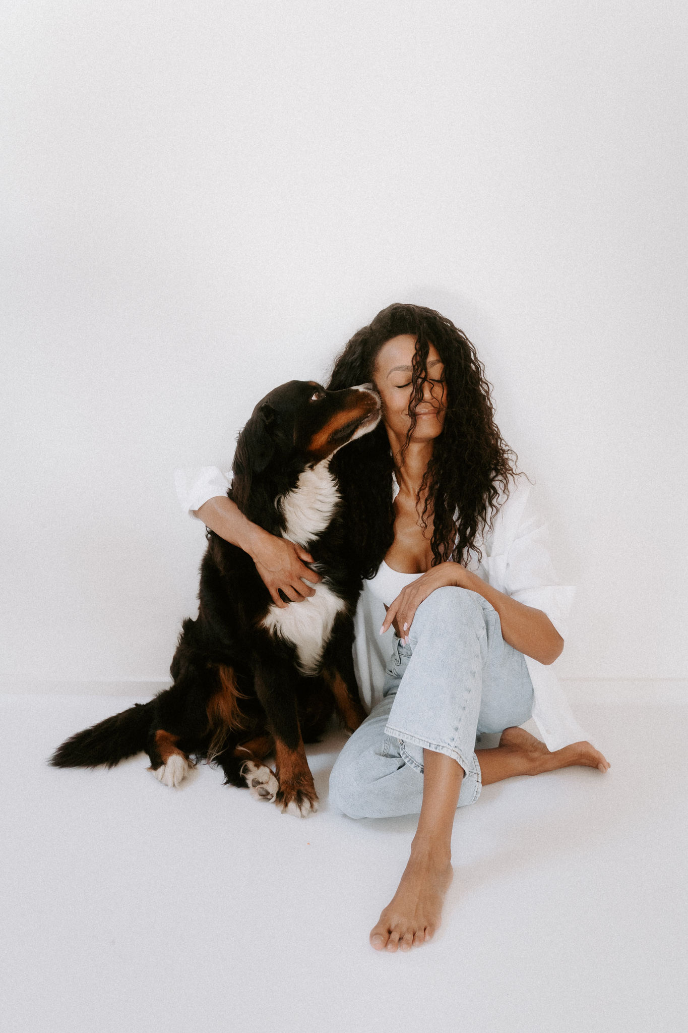 Eine Junge Frau wird von ihrem Bernersennenhund liebevoll angeschleckt